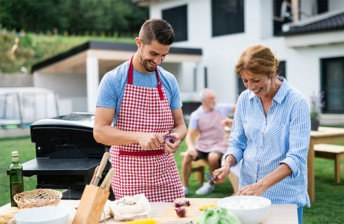 Man and his mom happily preparing food together outdoors, highlighting still just hurt and Mother's Day conflict.