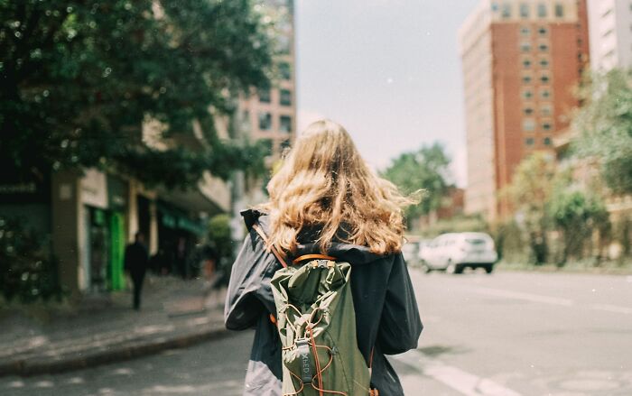Woman over 42 with a green backpack walking on a city street, symbolizing what women over 42 no longer tolerate.