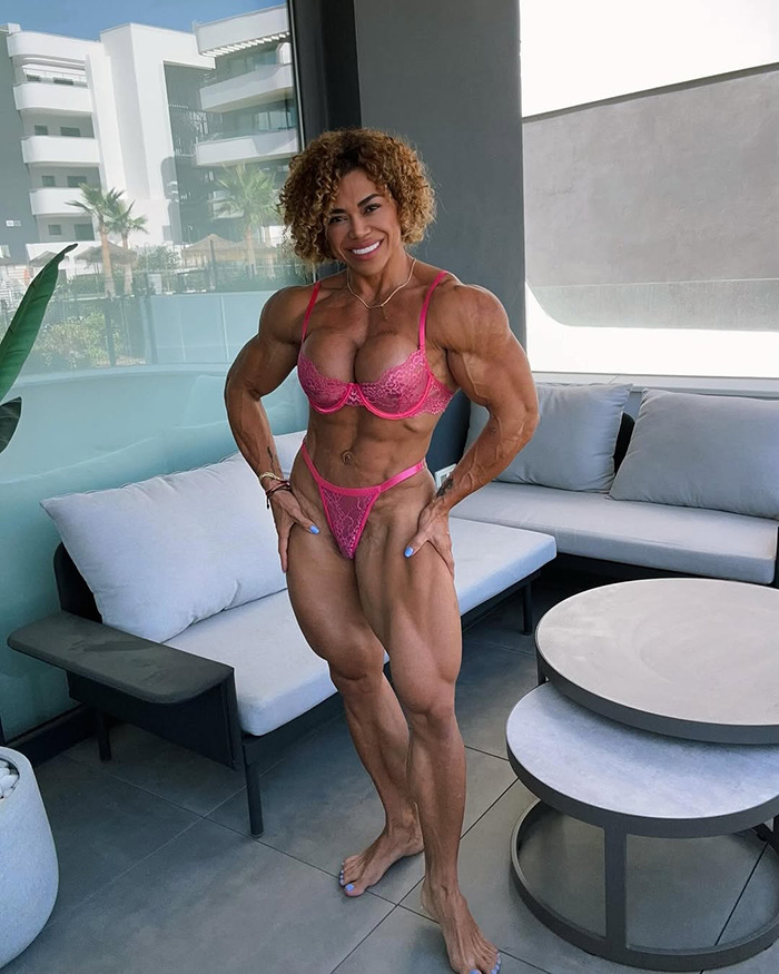 Female bodybuilder with muscular physique posing in pink lingerie on a balcony, representing bodybuilder dubbed She Hulk.