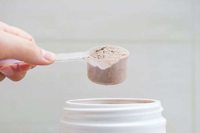 Hand holding a scoop of powder above an open container highlighting unexpected airport security issues with powders.