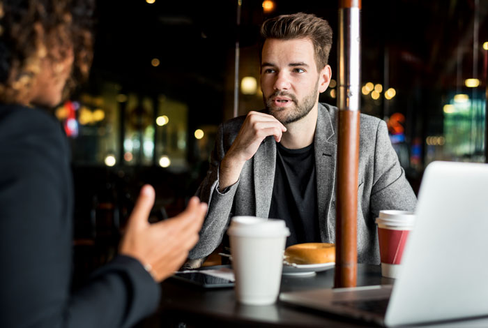 Man discussing big money projects confidently in a cafe setting during a business meeting.