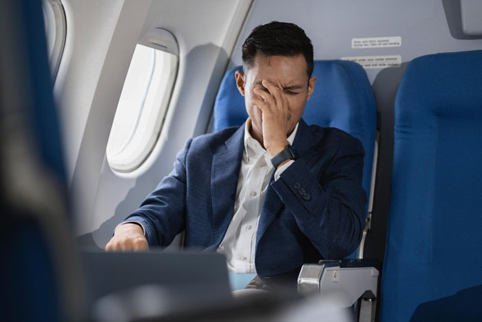 Man on airplane looking stressed after quizzing flight attendant on sensitive safety questions during flight. Man on airplane looking stressed after quizzing flight attendant on sensitive safety questions during flight.