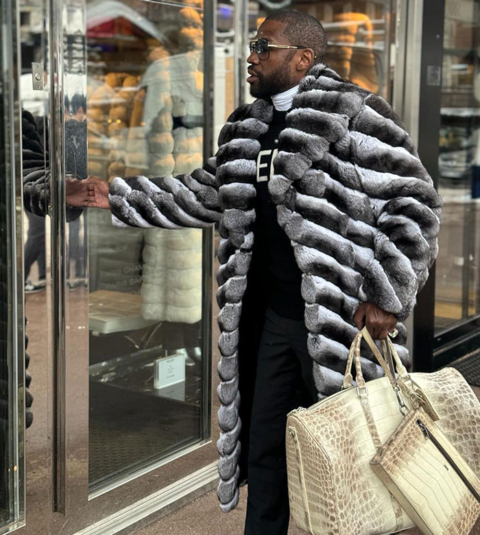 Floyd Mayweather wearing a luxury fur coat and sunglasses, carrying a large designer bag outside a store.
