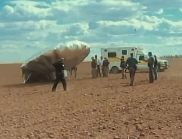 Balloon Boy family and emergency responders standing near deflated balloon in open field during infamous controversy.