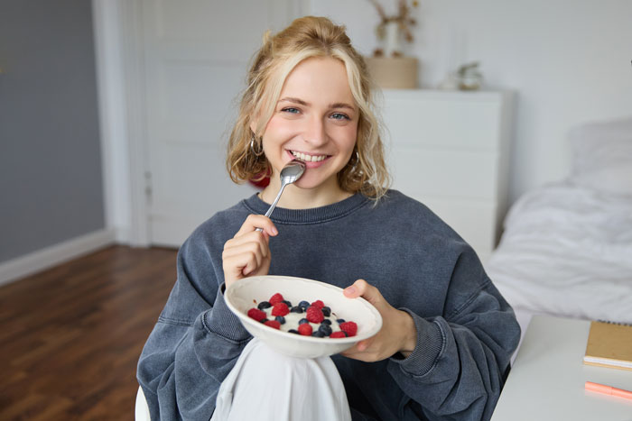 Young woman eating a bowl of fiber-rich berries, promoting the body&rsquo;s ability to get rid of cancer-causing forever chemicals