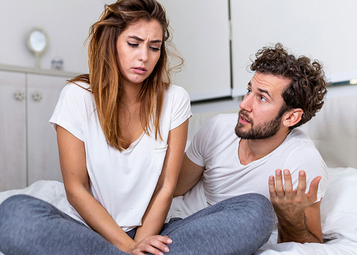Wife obsessed with having more kids sitting upset while husband discusses their marriage and family choices in bedroom. Wife obsessed with having more kids sitting upset while husband discusses their marriage and family choices in bedroom.