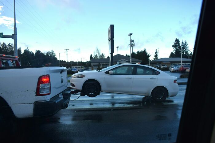 White car being towed by a truck on a wet street, illustrating epicly unhinged ways people got back at cheating exes.