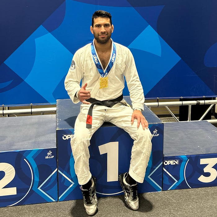 Male Jiu-Jitsu black-belt trainer wearing a medal sitting on the winner&rsquo;s podium after competition event.