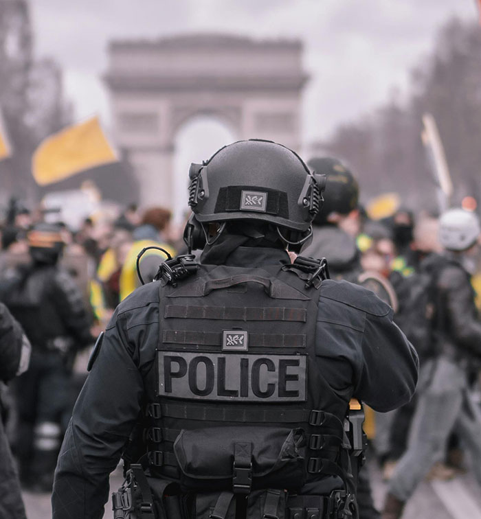 Police officer in tactical gear monitoring a crowded event, highlighting violence against women at a music festival incident.