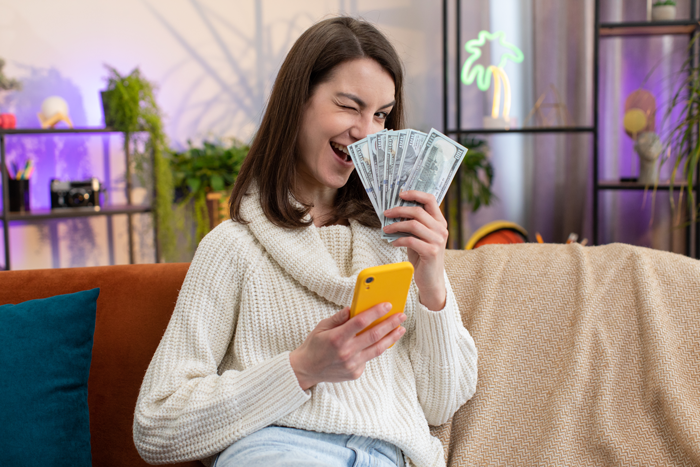 Woman holding cash and phone, winking with a playful expression, representing inheritance dispute and friendship conflict. Woman holding cash and phone, winking with a playful expression, representing inheritance dispute and friendship conflict.