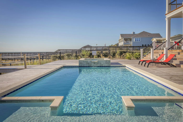 Outdoor pool at a beach house with lounge chairs on deck, perfect for a friend stepdaughter pool party gathering.