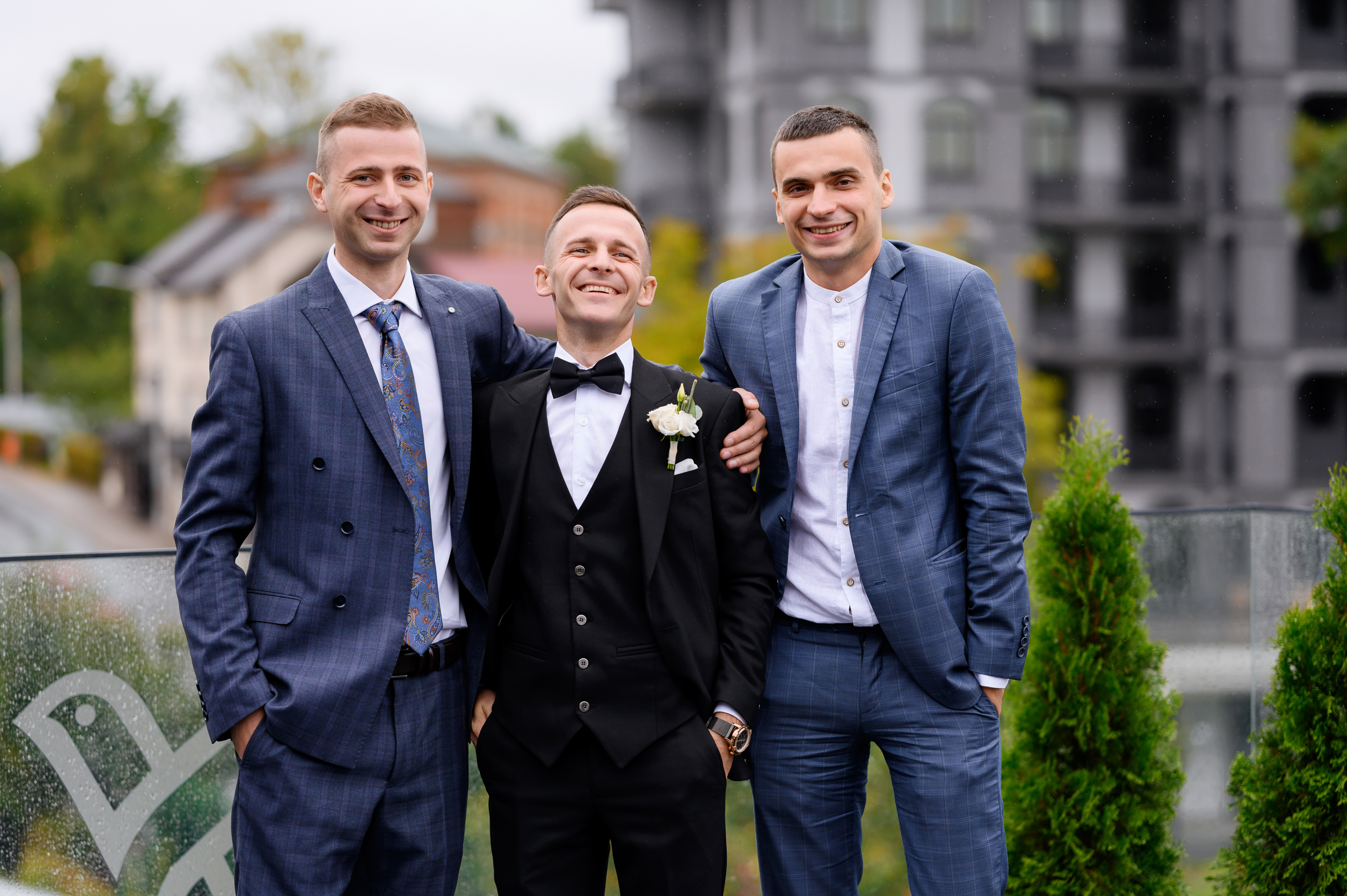 Three men in formal suits posing outside, representing excluding best man wedding photos over outfit concerns.