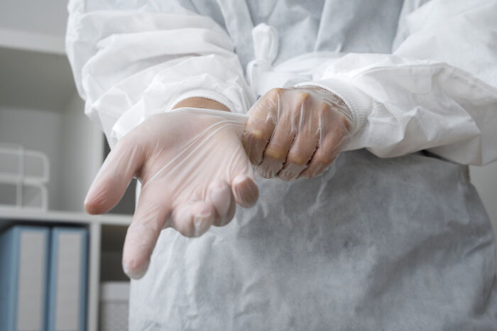 Medical professional putting on gloves preparing for autopsy with protective gown highlighting autopsy discoveries by doctors.