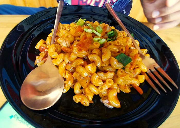 Plate of macaroni pasta with tomato sauce, garnished with green onions, highlighting funny and inappropriate kids' blurts shared by parents.