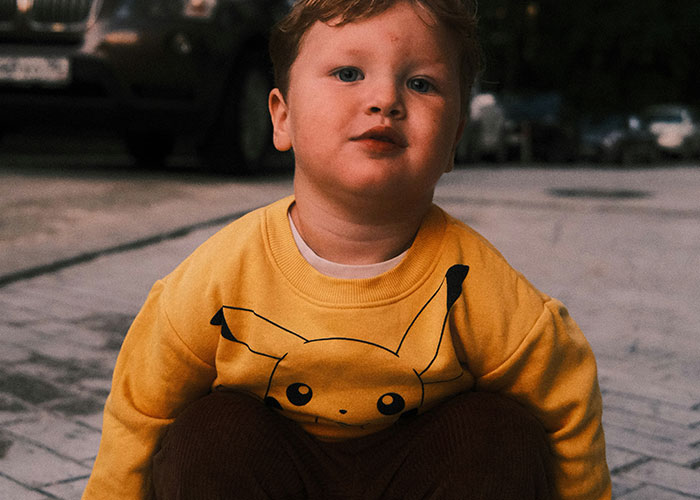 Young child in a yellow Pikachu sweatshirt outdoors, capturing the innocent and funny moments kids blurt out.