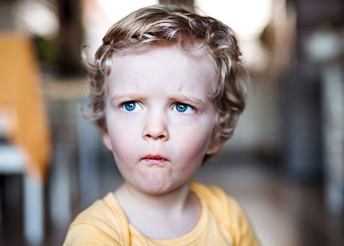Young boy with curly hair making a confused face, illustrating funny and inappropriate things kids have blurted out.