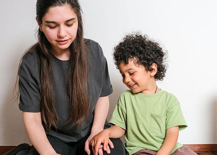 Woman and child sitting on floor smiling and interacting, capturing funny and inappropriate things kids have blurted out.