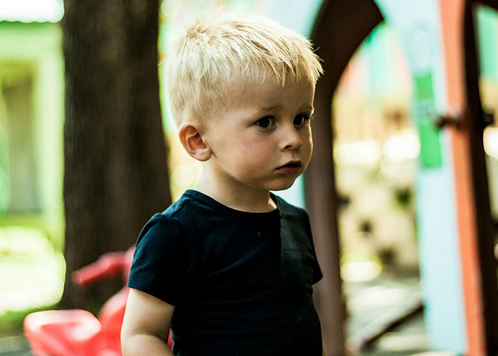 Young boy with blonde hair wearing black shirt outdoors, capturing funny and inappropriate things kids have blurted out moments.