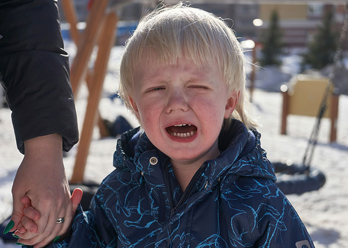Crying young child holding adult hand outdoors, illustrating funny and inappropriate things kids have blurted out moments.