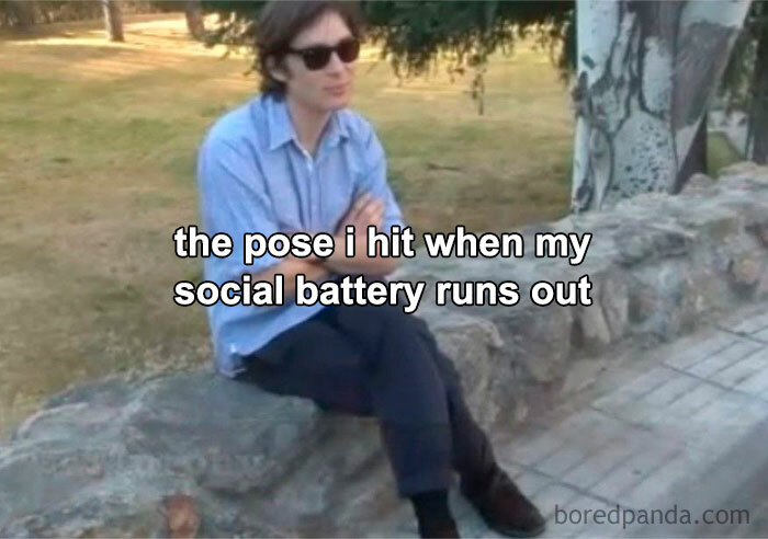 Person sitting alone outdoors with sunglasses captioned about social battery running out, reflecting introvert life memes.