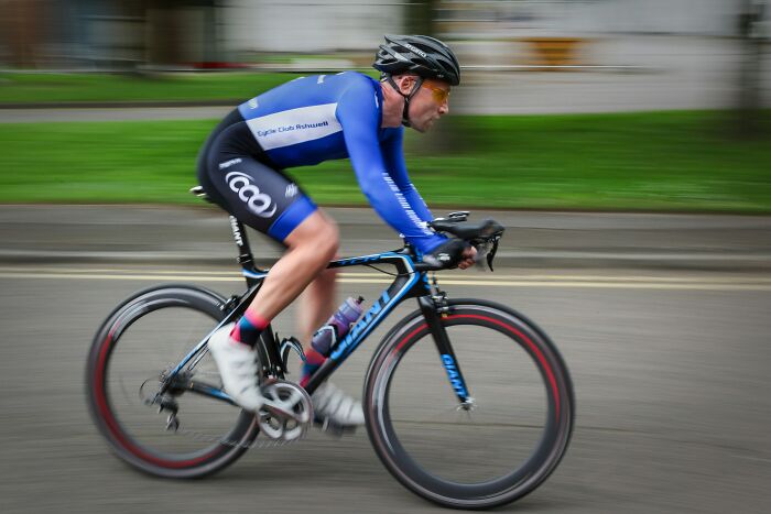 Cyclist in blue gear riding a road bike at high speed, illustrating active profession and dynamic lifestyle imagery. - 16