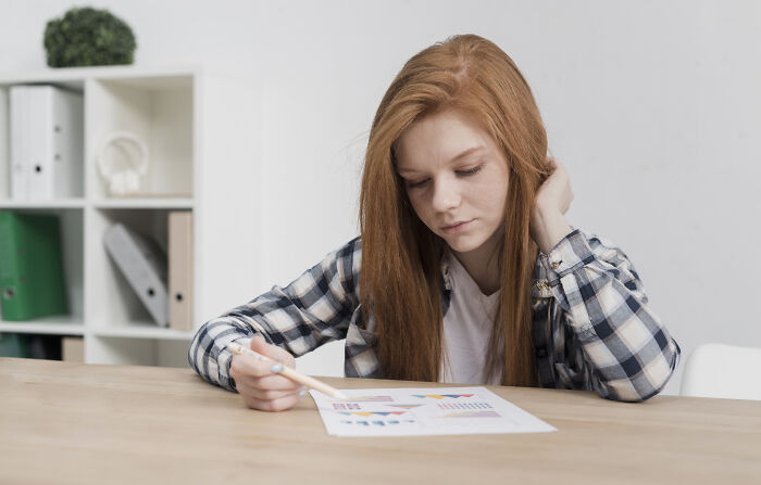 Young student looking frustrated while reviewing schoolwork, reflecting concerns about younger generations' declining abilities.