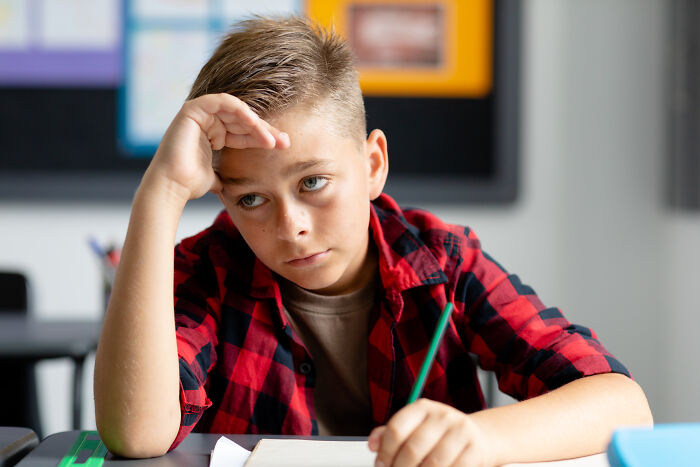 Young boy in a classroom showing frustration and distraction, illustrating teachers’ concerns about younger generations’ abilities.
