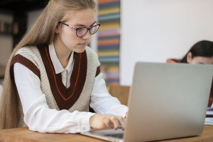 Student concentrating on a laptop in a classroom setting, highlighting concerns about younger generations’ abilities.