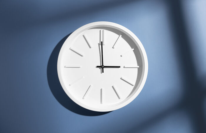 Minimalist white clock on a blue wall symbolizing time and decline in younger generations' abilities shared by teachers.