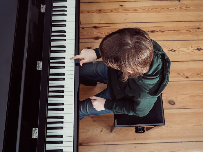 Student sitting at piano with finger on keys, illustrating teachers' concerns about the nose-diving abilities of younger generations.