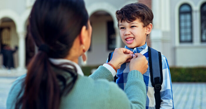 Teacher fixing young boy's shirt outside school, illustrating concerns about the nose-diving abilities of younger generations.