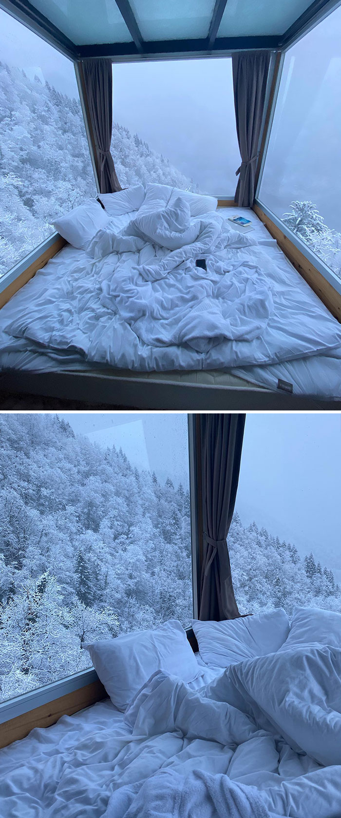 Hotel design featuring a cozy bed with large windows showcasing snowy mountain views in a creative setting.