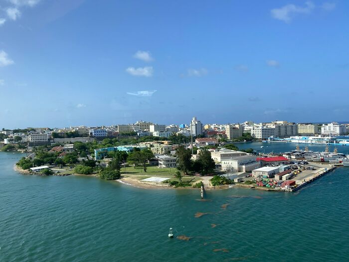 Coastal view of a crowded city harbor with buildings and docks under a bright blue sky, highlighting travel destinations.