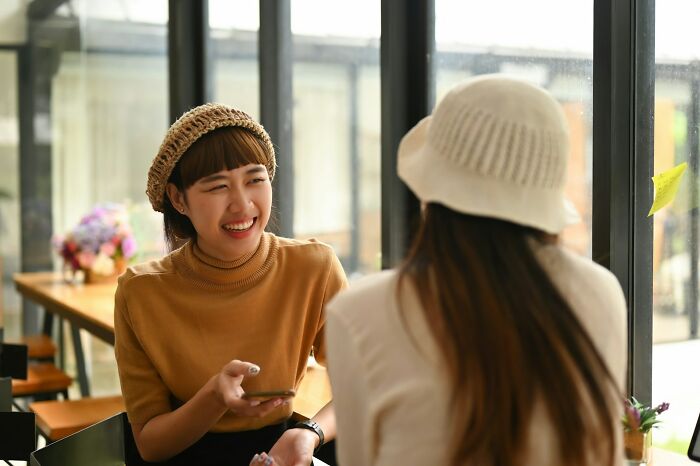 Two women chatting in a cafe, showing moments people realized their close friend was actually a total jerk.