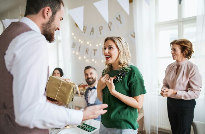 A man giving a gift to a woman at a birthday party, highlighting cultural no no actions in different countries.
