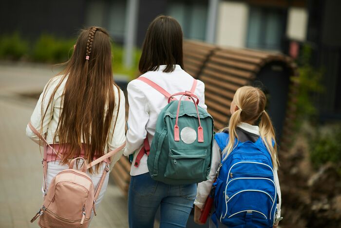 Three girls walking with backpacks outdoors, representing support and connection for postpartum OCD experiences in women.
