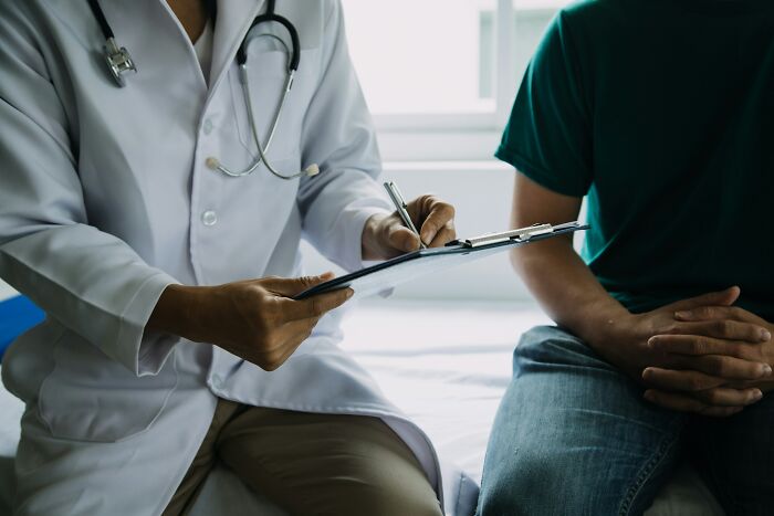 Doctor with stethoscope reviewing notes on clipboard while consulting a patient, highlighting tobacco health risks advice.