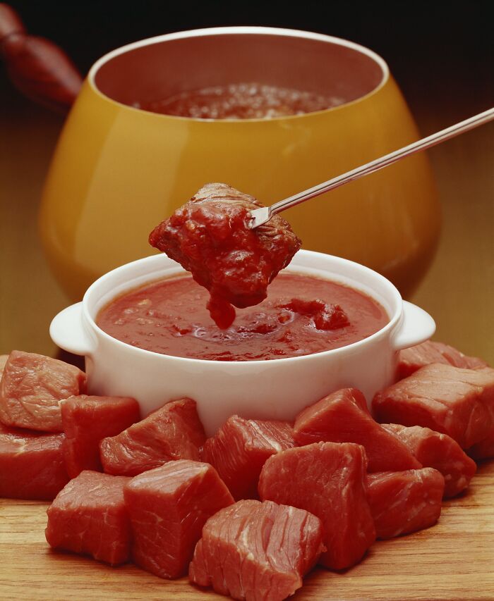 Raw meat cubes and tomato dipping sauce served with a fondue pot illustrating cultural no no food practices.