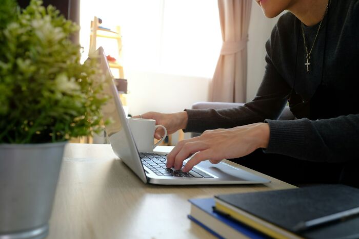 Person using laptop and holding coffee cup at desk, depicting scary online moments that left them traumatized.