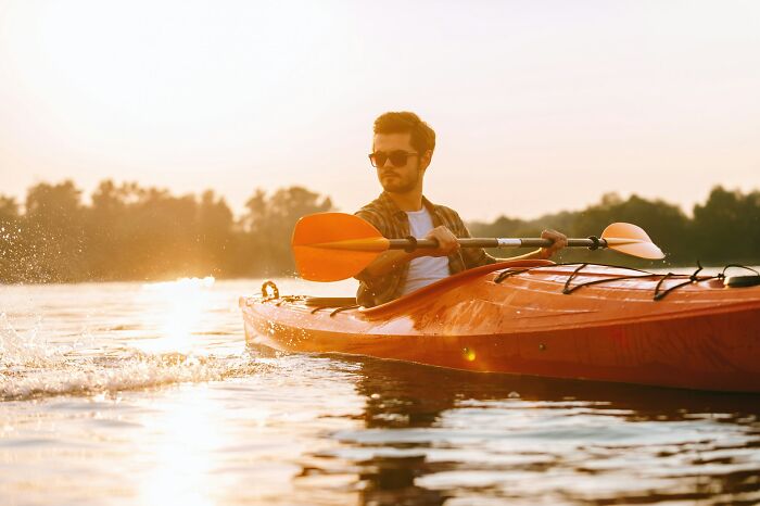 Man kayaking on calm water at sunset, symbolizing freedom after getting back at cheating exes in epic ways.