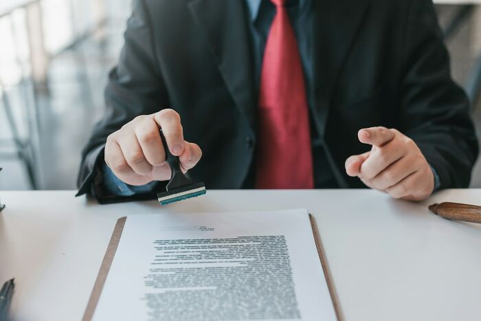 Man in suit stamping a document on a desk, symbolizing no peaceful solution to our current situation discussions.