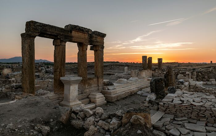 Ancient ruins at sunset with stone columns and remnants, evoking prehistoric and dinosaur facts exploration.