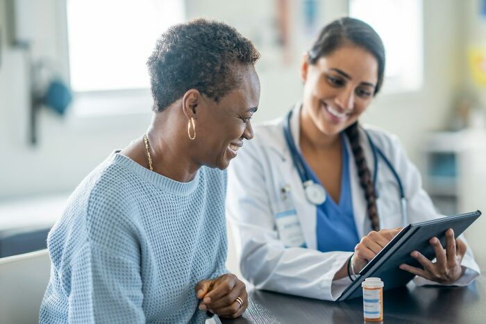 Woman consulting with a female doctor using a tablet, highlighting experiences with dismissive doctors in healthcare.
