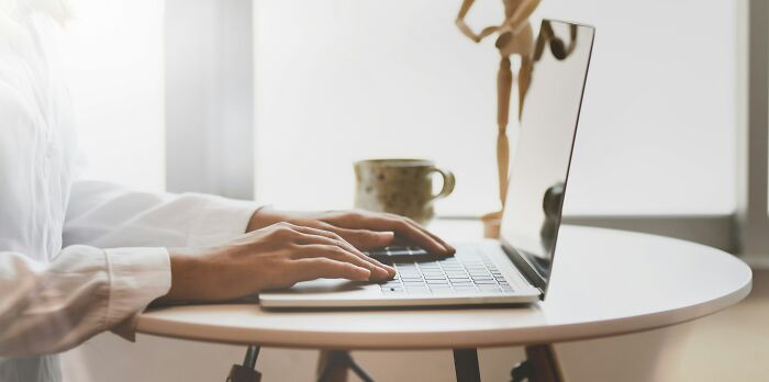 Person typing on a laptop at a round table, symbolizing scary online moments that left people traumatized.