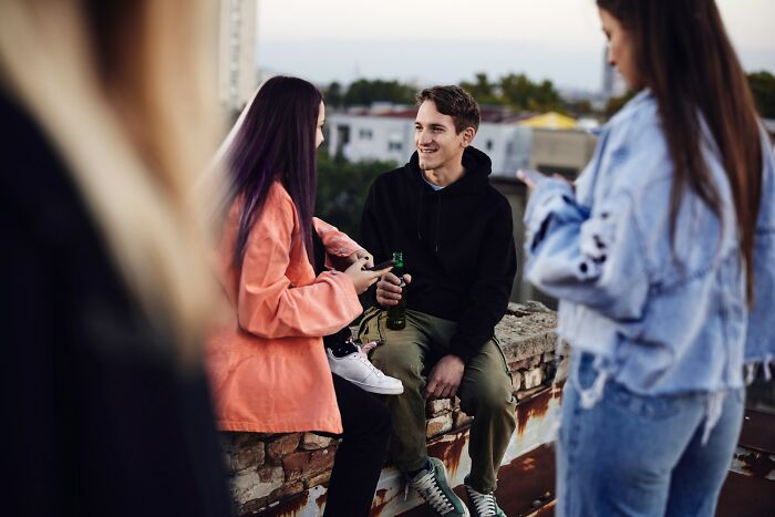 Young people socializing outdoors at sunset, illustrating challenges of modern dating and social interactions in urban settings.