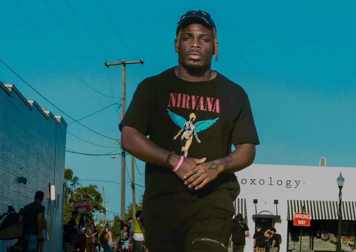 Man wearing a black Nirvana shirt walking outdoors, illustrating confident expression linked to girlfriend behaviour change relationship.