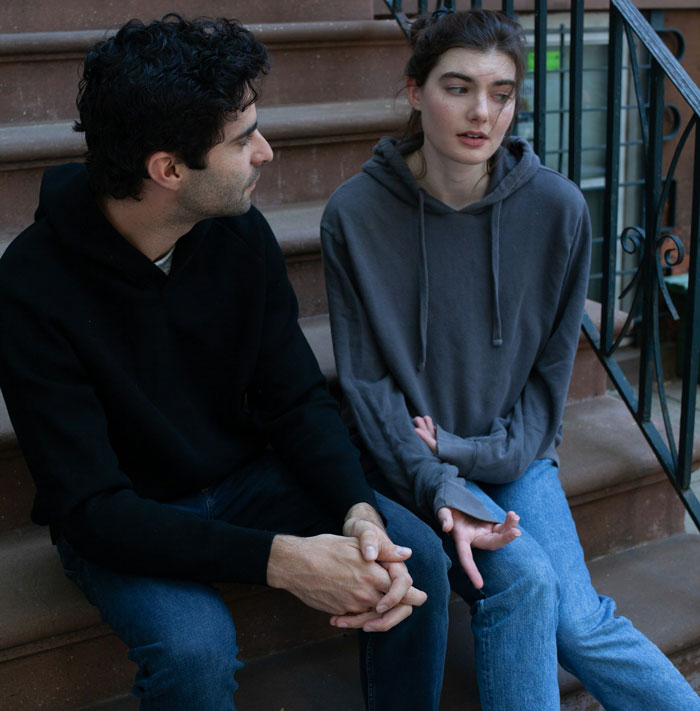 Man and woman sitting on outdoor steps, appearing to have a serious conversation about transphobia support.