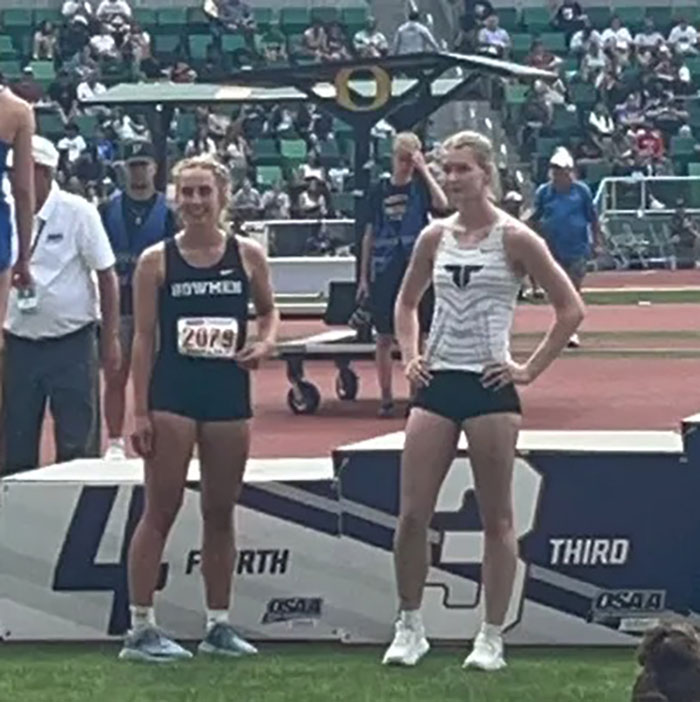 Two female athletes standing near a podium at a track event, highlighting support for transgender athlete. Two female athletes standing near a podium at a track event, highlighting support for transgender athlete.