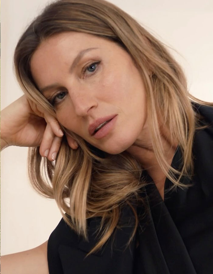 Gisele Bundchen in a close-up portrait with natural makeup and loose hair, highlighting her serious expression.