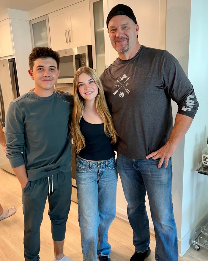 Beloved child star from Good Luck Charlie posing with two men in casual outfits inside a modern kitchen.